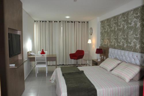 a bedroom with a bed and a desk and a chair at Betel Beach Flat Boa Viagem in Recife