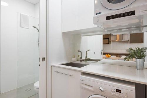 a white kitchen with a sink and a microwave at BRID243FL - The Terrace on Bridge in Sydney