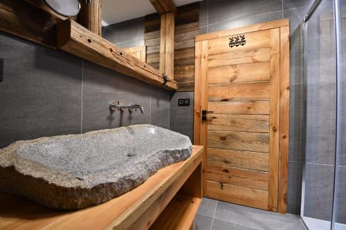 uma casa de banho com uma grande banheira de pedra e uma porta de madeira em Chalet Apartments Maštal em Železná Ruda