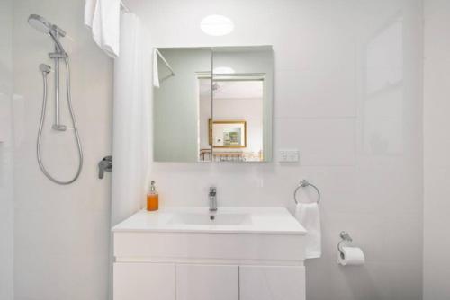 a white bathroom with a sink and a mirror at BRID243FL-G - Converted Garage on Foss - King Bed in Sydney