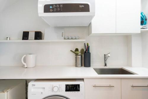 a white kitchen with a sink and a dishwasher at BRID243FL-G - Converted Garage on Foss - King Bed in Sydney