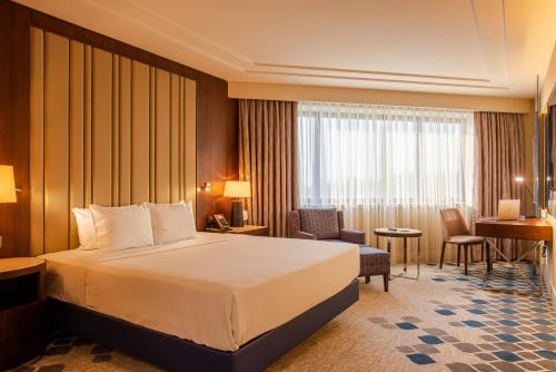 a hotel room with a bed and a desk at AZIMUT Grand Hotel Tashkent in Tashkent