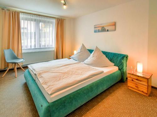ein Schlafzimmer mit einem grünen Bett mit einem Stuhl und einem Fenster in der Unterkunft Modern Apartment in Klutz with Sea Nearby in Klütz