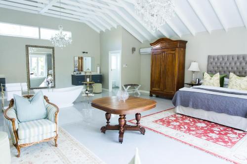 a bedroom with a bed and a table and a tub at Burkleigh House in Johannesburg