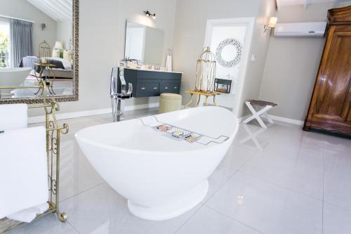 a bathroom with a white bath tub and a mirror at Burkleigh House in Johannesburg