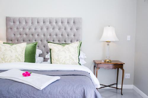 a bedroom with a large bed with green and white pillows at Burkleigh House in Johannesburg
