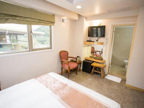 a bedroom with a bed and a window and a bathroom at Mei Jia Mei Hotel in Jiaoxi