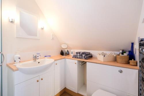 a white bathroom with a sink and a mirror at The Bay Tree Studio in Thorpeness