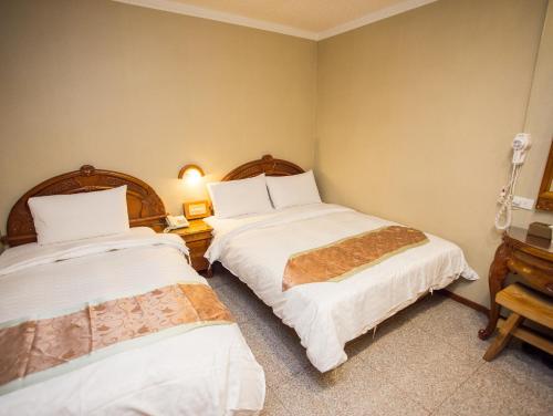 a bedroom with two beds with white sheets at Mei Jia Mei Hotel in Jiaoxi