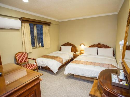 a hotel room with two beds and a desk at Mei Jia Mei Hotel in Jiaoxi