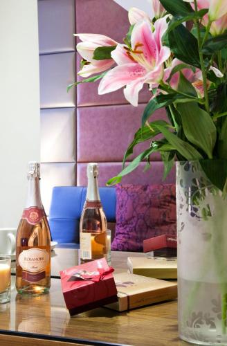 a table with two bottles of wine and a vase with flowers at City Inn Russell Square in London