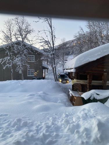 a pile of snow next to a house with a car at Villa Solsiden Geilo in Geilo