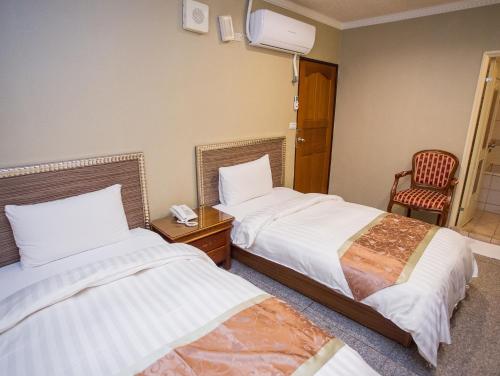 a hotel room with two beds and a chair at Mei Jia Mei Hotel in Jiaoxi