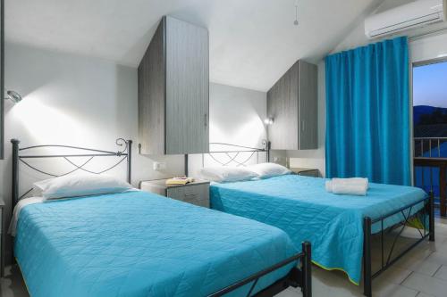 two beds in a room with blue sheets at Studio Timotheos in Marathias