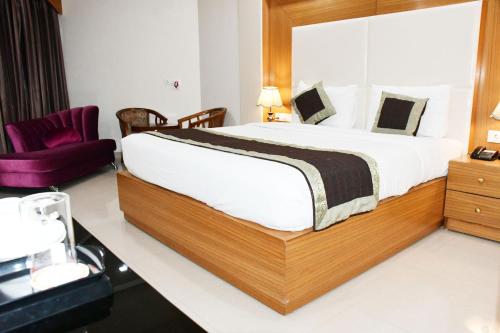 a bedroom with a large bed and a purple chair at HOTEL ANAND INTERNATIONAL in Bodh Gaya