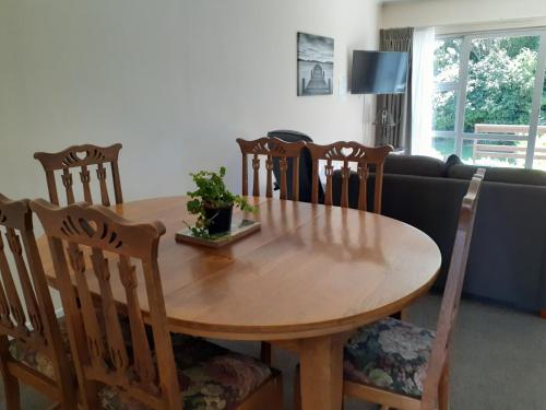 a wooden dining room table with chairs and a couch at Golden Bay Motel in Takaka