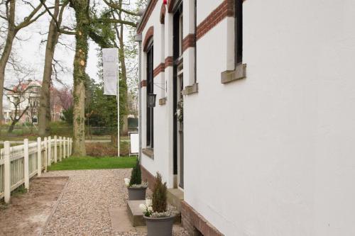a white building with potted plants next to a fence at Bed & Breakfast Rijsterbosch in Rijs