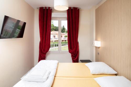 グリモーにあるSOWELL RESIDENCES Les Perles de Saint Tropezのベッドルーム1室(ベッド2台付)、赤いカーテン付きの窓が備わります。