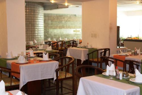 uma sala de jantar com mesas e cadeiras com toalha de mesa branca em Aram Beach Boa Viagem no Recife