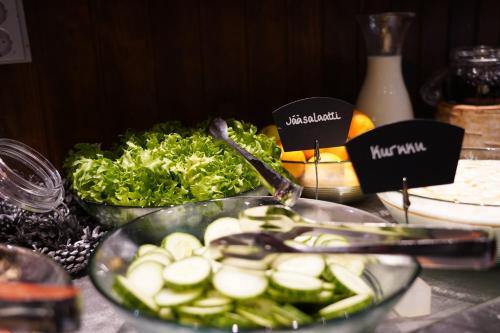 Una mesa con un bol de pepinos y otras verduras. en Santa's Hotel Aurora & Igloos, en Luosto