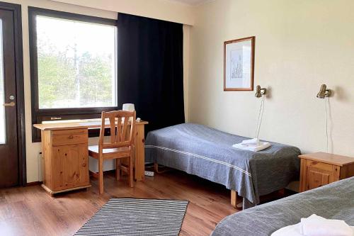 a room with a bed and a desk and a window at Motel Patalahti in Jämsä