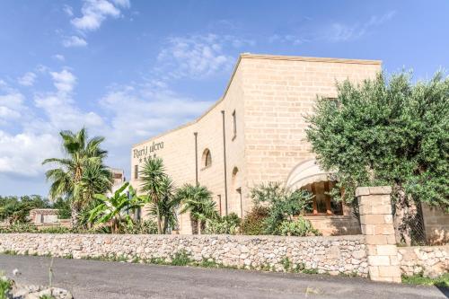 a brick building with palm trees in front of it at Masseria Ruri Pulcra in Patù
