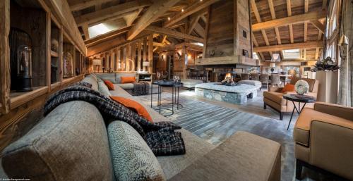 un grand salon avec des canapés et une cheminée dans l'établissement MGM Hôtels & Résidences - Chalet La Ferme de Juliette, au Grand-Bornand