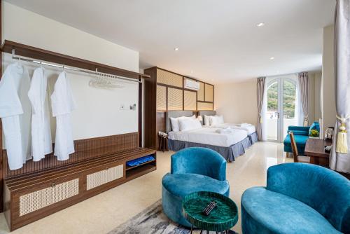 a hotel room with a bed and two blue chairs at Aquatel Vung Tau in Vung Tau