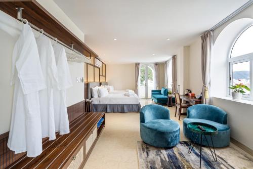 a bedroom with a bed and two blue chairs at Aquatel Vung Tau in Vung Tau