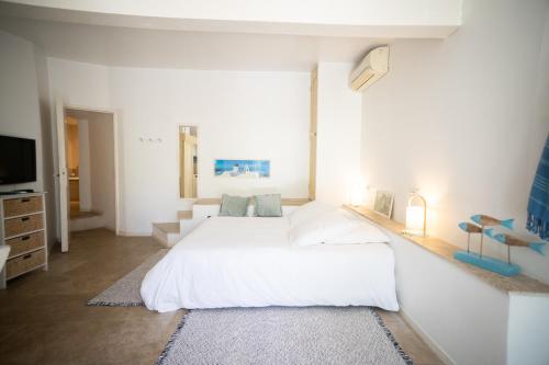 a white bedroom with a large bed and a tv at Le Mas du Cheval in Lattes