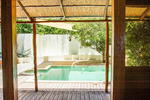 a house with a swimming pool with a pergola at Tree House Villa in Praia do Tofo