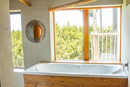 a bath tub in a bathroom with a window at Tree House Villa in Praia do Tofo