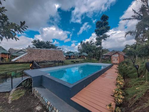 a swimming pool with a wooden walkway next to a house at Your Brothers House Tribal Village in Legazpi