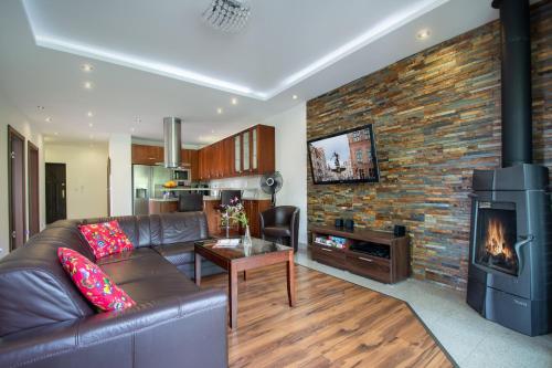 uma sala de estar com um sofá de couro e uma lareira em Rezydencja Wind Rose - luxury ApartHotel Gdansk em Gdansk