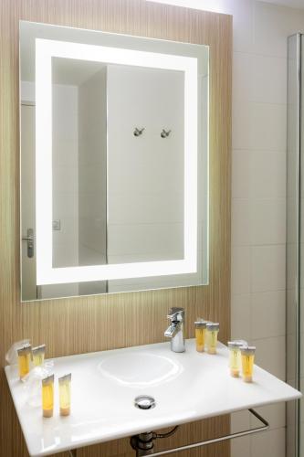 La salle de bains est pourvue d'un lavabo et d'un grand miroir. dans l'établissement SOWELL HÔTELS du Golfe de Saint-Tropez, à Grimaud