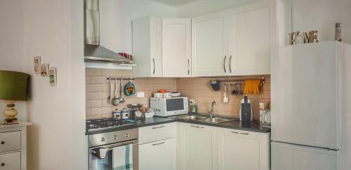 a kitchen with white cabinets and a white refrigerator at BecoHouse in Rome