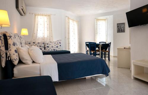 um quarto com uma cama, uma mesa e cadeiras em Villea Village em Makry Gialos