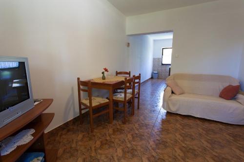 a living room with a table and a couch and a television at Apartments Draga in Vantačići