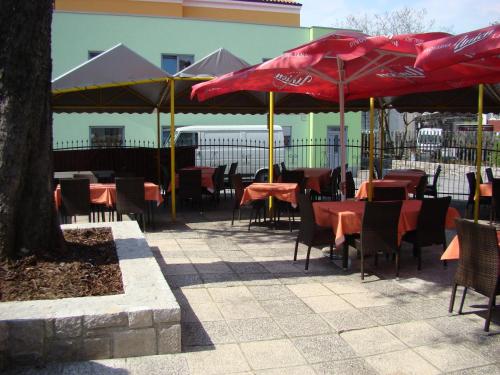 a group of tables and chairs with red umbrellas at Gostilna pri Dragici, gostilna s prenočišči, d.o.o. in Sežana