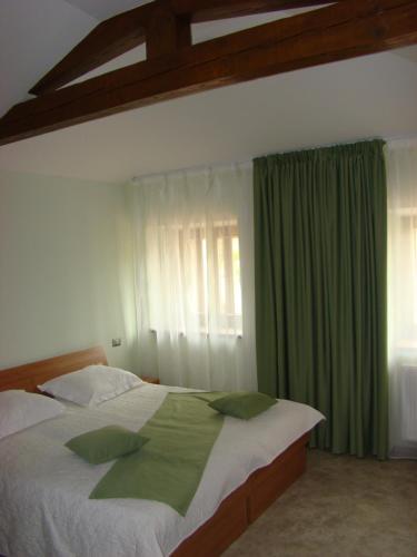 - une chambre avec un grand lit et un rideau vert dans l'établissement Gostilna pri Dragici, gostilna s prenočišči, d.o.o., à Sežana