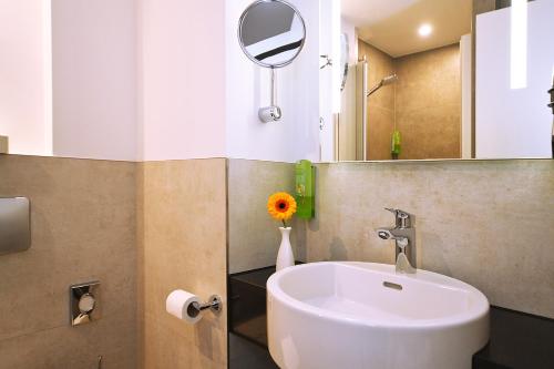 ein Badezimmer mit Waschbecken und Spiegel in der Unterkunft GenoHotel Karlsruhe in Karlsruhe