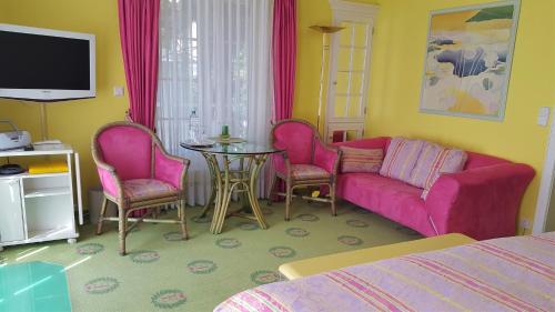 - une chambre dotée d'un mobilier rose, d'une table et de chaises dans l'établissement Boutique Hotel Villa am See, à Hagnau am Bodensee