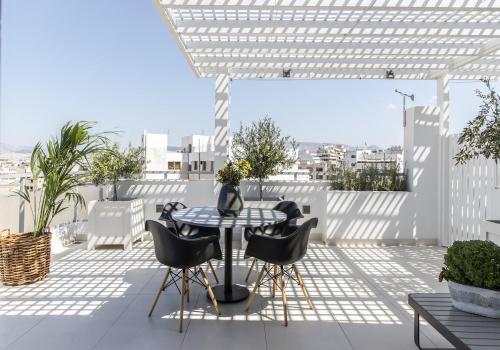 a patio with a table and chairs on a roof at Gallery Suites & Residences Piraeus in Piraeus