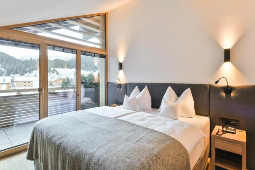 a bedroom with a large bed and a large window at Hotel Sonnblick in Lech am Arlberg