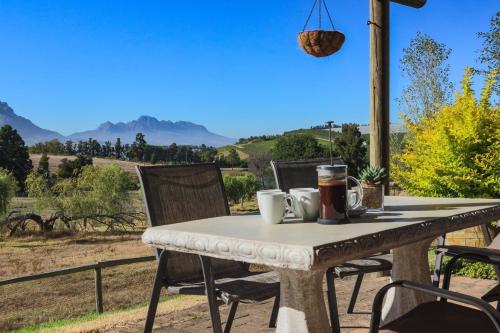 a table with two mugs of coffee on a patio with a view at Zebra Cottage and Lodge in Stellenbosch