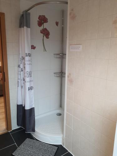 a shower with a shower curtain with a flower on it at Ferienwohnung am Jordan in Schneverdingen