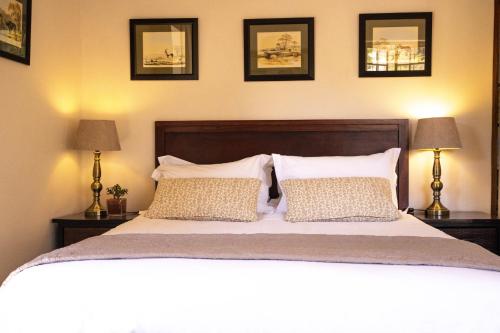 a bedroom with a large bed with three pictures on the wall at Zebra Cottage and Lodge in Stellenbosch