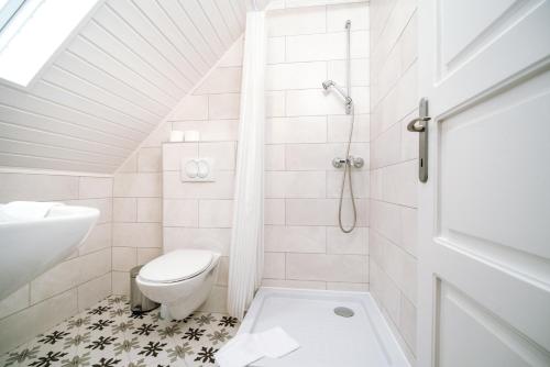 a white bathroom with a toilet and a sink at Topáz Apartmanházak in Balatongyörök