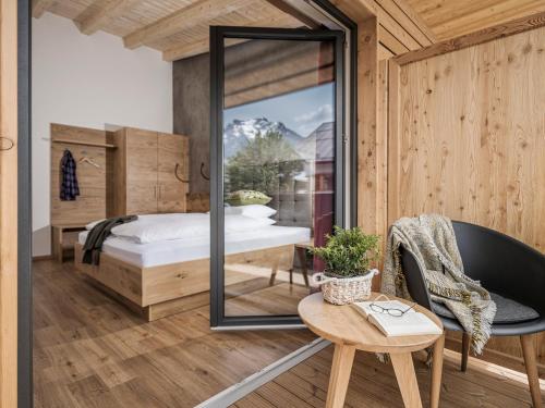 1 dormitorio con espejo, 1 cama y 1 silla en Mo's Apartments, en Mayrhofen