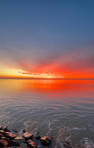 um pôr-do-sol sobre o oceano com pedras na água em Appartement "Envies D'ailleurs" Vue Mer em Saint-Brévin-les-Pins